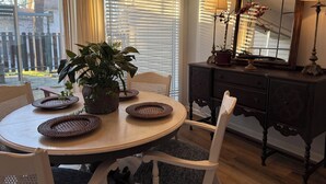 Un comedor con una mesa redonda, sillas, una planta en maceta y un mueble de madera oscura con espejo.