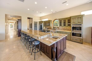 A spacious kitchen with a large island, bar stools, and modern appliances.