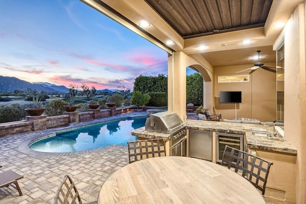 An outdoor patio with a pool, bar, and seating area.