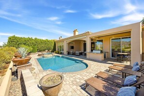 A modern house with a swimming pool, outdoor seating, and a patio area.