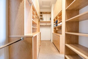 A walk-in closet with wooden shelving and drawers.