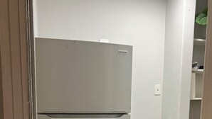 A white refrigerator in a corner, a black trash bin, and a grey rug on a wooden floor. - Cozy Apartment Little Rock Pets Welcome (Little Rock)