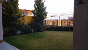 A courtyard with a lawn, a yellow building, and a decorative fence. - HOTEL CONSTITUCION (Mineral del Monte)