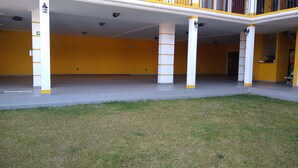 A covered outdoor area with a tiled floor, yellow walls, and white pillars with yellow bands. - HOTEL CONSTITUCION (Mineral del Monte)