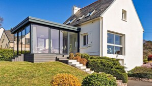 A modern house with a glass conservatory, a white exterior, and a sloped roof. - Cozy home in Erquy with WiFi (Erquy)