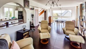 A spacious living area with two leather armchairs, a dining table, and a kitchen area with a refrigerator and microwave. - Cozy home in Erquy with WiFi (Erquy)