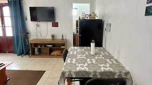 A living room with a TV, a dining table, and a sofa.