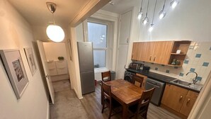 Eine kompakte Küche mit Esstisch, Holzschränken, einem Kühlschrank und einer Waschmaschine.