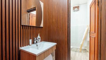 A bathroom with a wooden vanity, a sink, a mirror, and a towel rack.