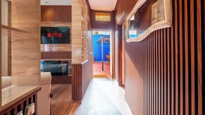 Un pasillo con paneles de madera, un letrero de Netflix y una vista parcial de una habitación con pared azul y una escalera.