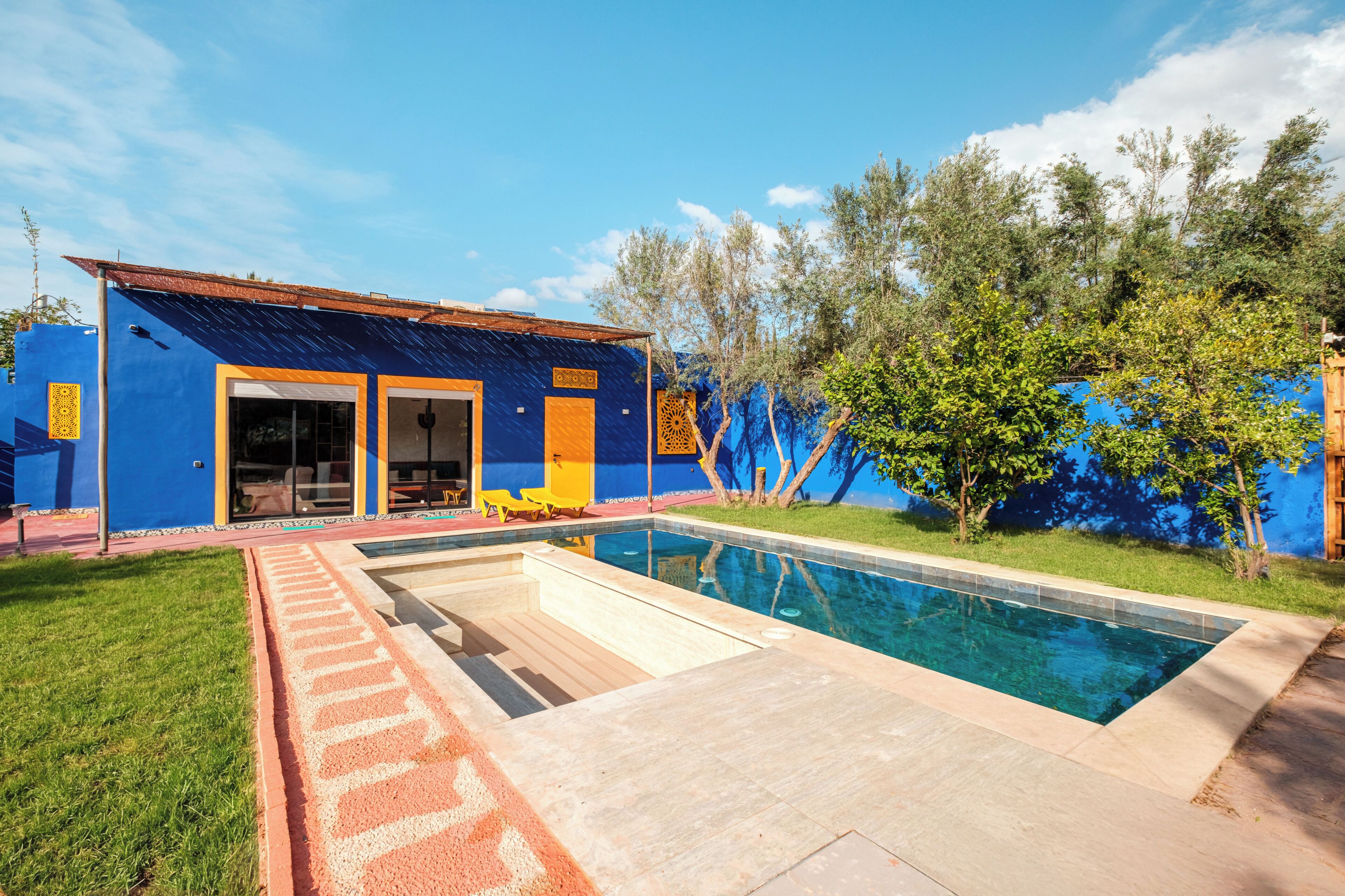 A modern building with a pool, a covered patio, and a blue exterior.