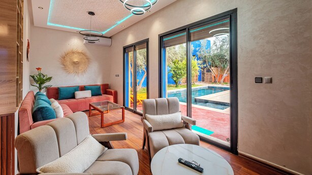 Una sala de estar moderna con un sofá, sillones, una mesa de centro y vista a la piscina.