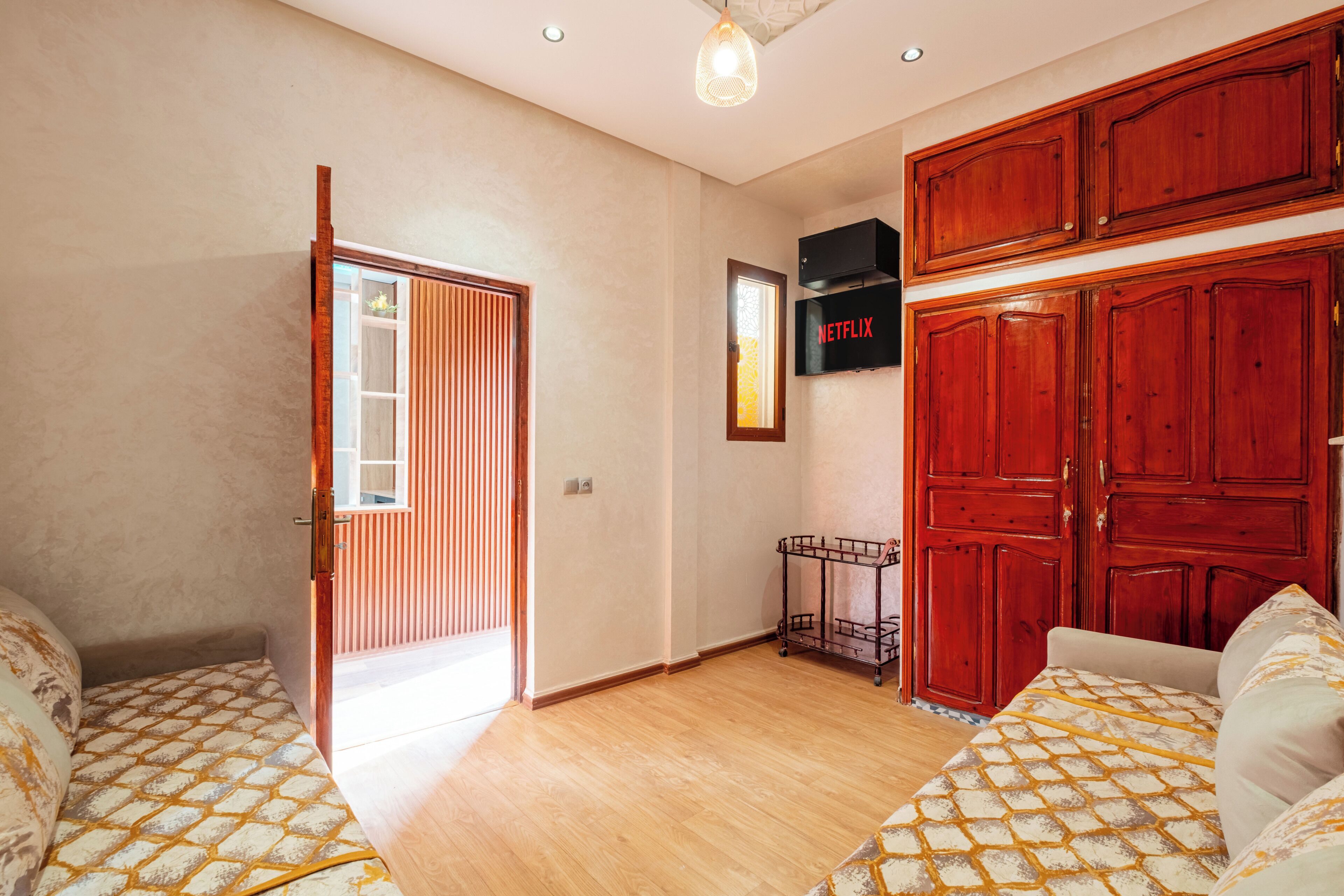 A room with a bed, a wardrobe, a TV, and a door leading to another room.