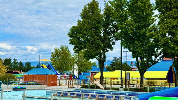 A swimming pool with a blue and green slide, surrounded by trees and a building with a yellow roof. - Close to West Valley Hospital and Golf course in Caldwell, ID (Caldwell)