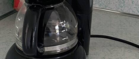 Una cafetera Mr. Coffee negra amb un recipient de vidre transparent, un botó d'encesa verd i un indicador de temporitzador.