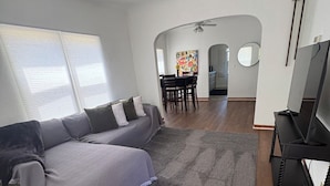 A living room with a sofa, a TV, and a dining area with chairs and a table. - Close to West Valley Hospital and Golf course in Caldwell, ID (Caldwell)