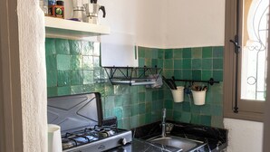 Eine Küche mit Gaskochfeld, Spüle und einer grünen Fliesenwand.