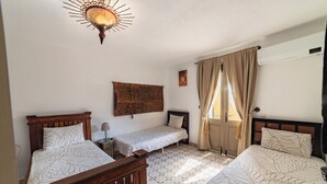 Ein Schlafzimmer mit zwei Einzelbetten, einem Holz-Kopfteil, einem gemusterten Boden und einer Wandleuchte.
