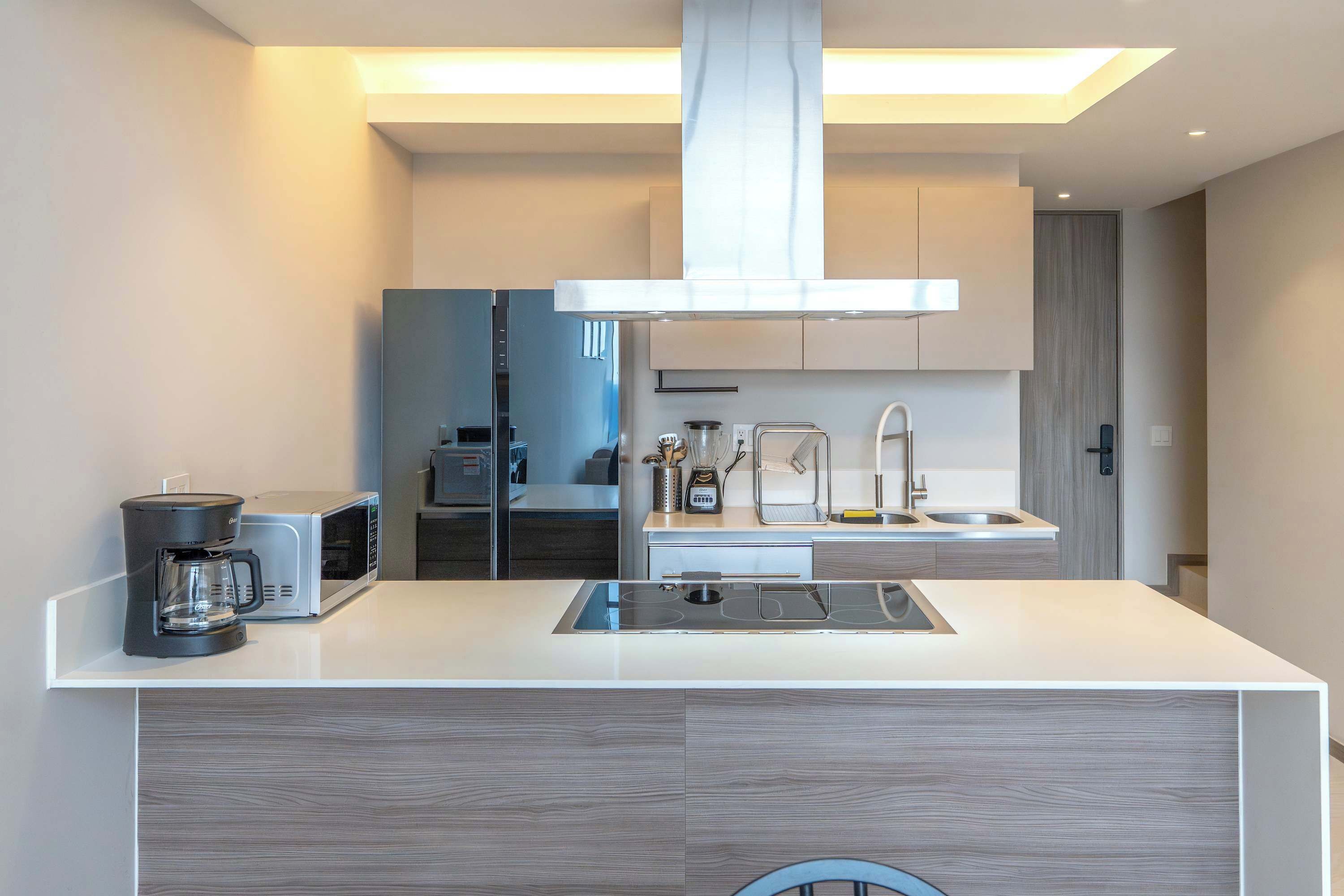 Una cocina moderna con una isla central, microondas integrado y electrodomésticos de acero inoxidable.