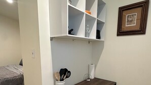 A small room with a wooden table, a white shelf unit, a framed picture on the wall, and a bed in the background. - Cozy 1-bedroom guest house studio in marvelous Lancaster (Lancaster)