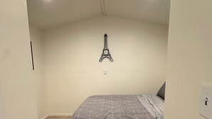 A bedroom with a bed, a wall-mounted Eiffel Tower decoration, and a wooden floor. - Cozy 1-bedroom guest house studio in marvelous Lancaster (Lancaster)