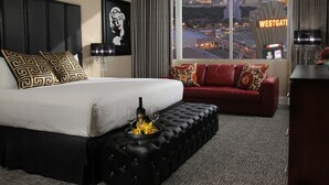 Ett hotellrum med en säng, en röd soffa, utsikt över stadsbilden och en Westgate-skylt.