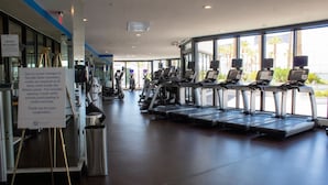 Ett träningscenter med löpband, träningsutrustning och en skylt som anger att det är obligatoriskt att använda munskydd.