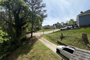 A residential driveway with a pathway leading to a house, a parked sports car, and a white truck in the background. - Cozy 3BR Home | King Bed + Smart TVs + Laundry (Charlotte)
