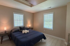 A bedroom with a bed, two nightstands, two bedside lamps, and two windows with blinds. - Cozy 3BR Home | King Bed + Smart TVs + Laundry (Charlotte)