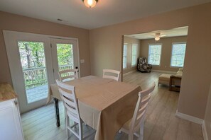 A dining area with a table and chairs, a ceiling fan, and a view through a door to an outdoor deck. - Cozy 3BR Home | King Bed + Smart TVs + Laundry (Charlotte)