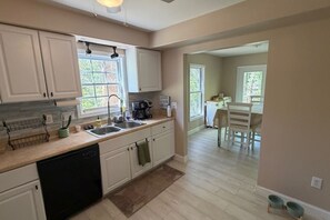 A kitchen with white cabinets, a dishwasher, a coffee maker, and a sink. - Cozy 3BR Home | King Bed + Smart TVs + Laundry (Charlotte)