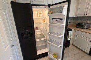 Een keuken met een zwarte koelkast, witte kasten en een broodrooster op het aanrecht.