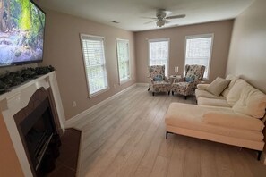 A living room with a fireplace, a television, a ceiling fan, and a sofa. - Cozy 3BR Home | King Bed + Smart TVs + Laundry (Charlotte)