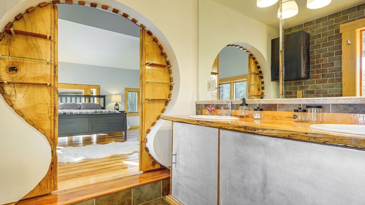 Un baño moderno con un espejo grande, tocador de madera y vista al dormitorio.