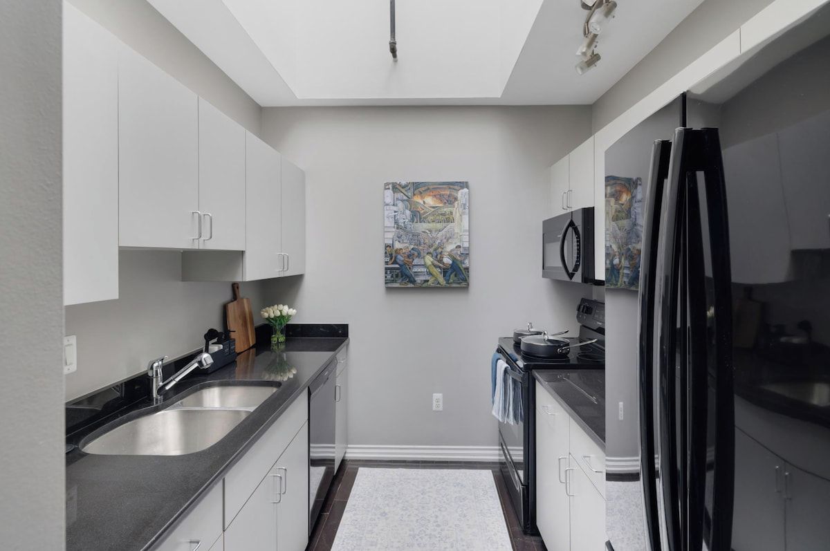 Une cuisine moderne avec un îlot central, des appareils électroménagers en acier inoxydable et un tableau accroché au mur.