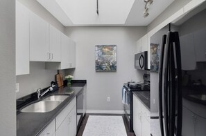 A modern kitchen with a central island, stainless steel appliances, and a painting on the wall.