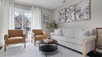 A living room with a sofa, two armchairs, a coffee table, and artwork on the wall.