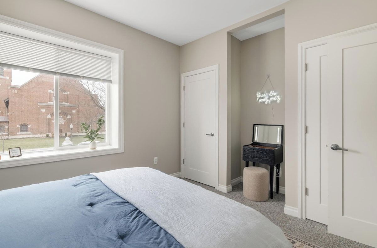 Une chambre à coucher avec un lit, une commode, un miroir et une fenêtre avec des stores.
