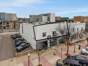 A building with a storefront labeled 'OPEN' and a parking lot with several cars.
