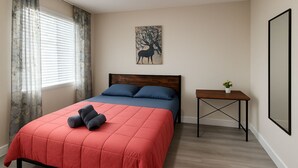 A bedroom with a bed, a nightstand, a painting, and a window with curtains. - Paradiso Shores (Miami)