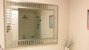 A bathroom with a large mirror, a sink, dark cabinets, and a toilet. - Paradiso Shores (Miami)