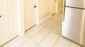 A kitchen with white cabinets, a stainless steel refrigerator, and a tiled floor. - Paradiso Shores (Miami)