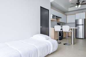 A modern, compact room with a bed, a kitchenette, and a ceiling fan. - ¡Nuevo y Céntrico con Gym! - 2 Cama Queen + Wifi (Monterrey)