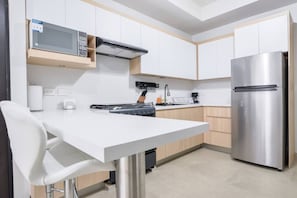 A modern kitchen with white cabinets, a stainless steel refrigerator, a microwave, and a gas stove. - ¡Nuevo y Céntrico con Gym! - 2 Cama Queen + Wifi (Monterrey)