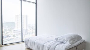 Una habitación con cama, ventana grande y vista a la ciudad.