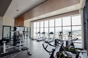 A gym with cardio machines, weight equipment, and a large window with a city view. - ¡Nuevo y Céntrico con Gym! - 2 Cama Queen + Wifi (Monterrey)