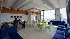 A modern office space with a high ceiling, large windows, and a mix of seating areas including a blue sofa and green chairs. - Obra de Arte y un Increíble, Amplio Departamento (Monterrey)