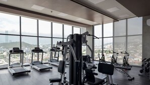 A gym with treadmills, weight machines, and stationary bikes, large windows with a city view. - Obra de Arte y un Increíble, Amplio Departamento (Monterrey)