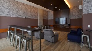 A modern living room with a brick wall, a flat-screen TV, a sofa, a dining table with bar stools, and a wooden floor. - Obra de Arte y un Increíble, Amplio Departamento (Monterrey)