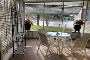 A covered patio with a table and chairs, a metal rack, and a view of a lake. - 3-bedroom mobile home in adorable Lady Lake with AC (Lady Lake)